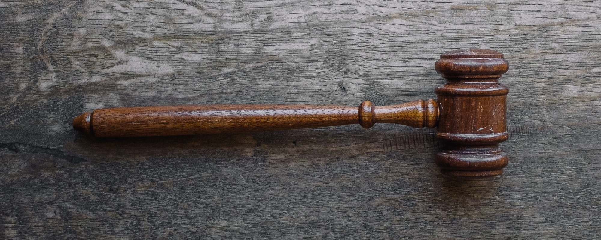 A wooden gavel lies on a wooden table (image by Wesley Tingey, Unsplash)