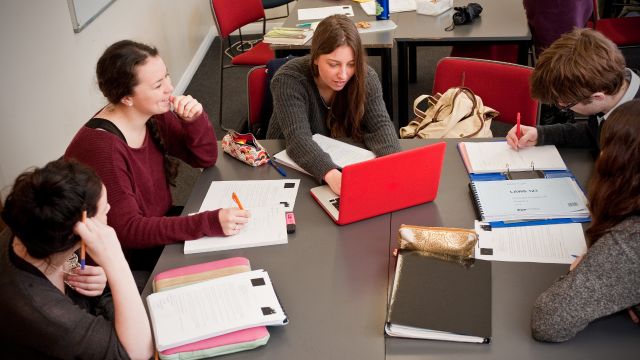 Man taking notes on note pad with open laptop