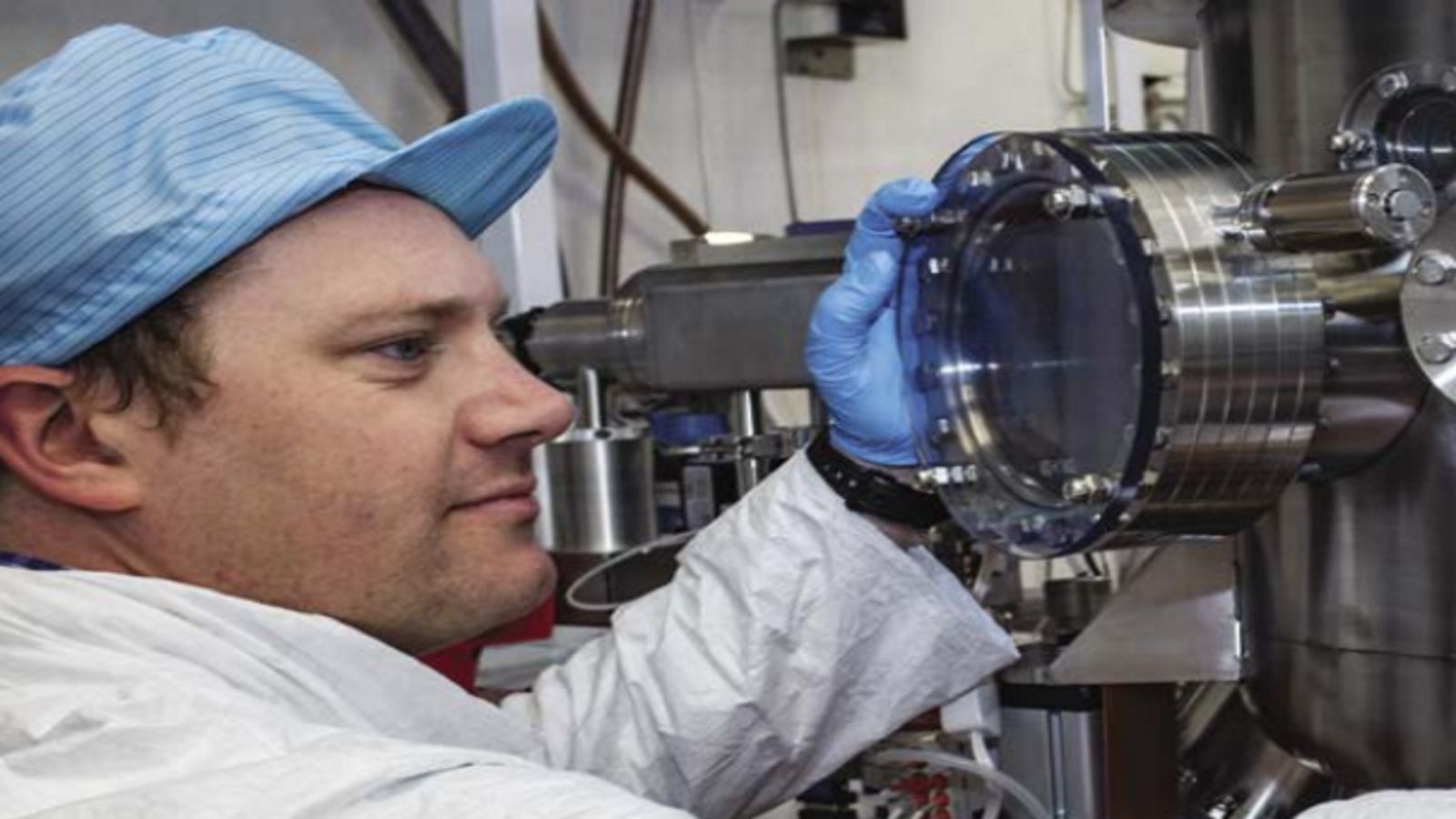 Scientist looking into vacuum chamber window.