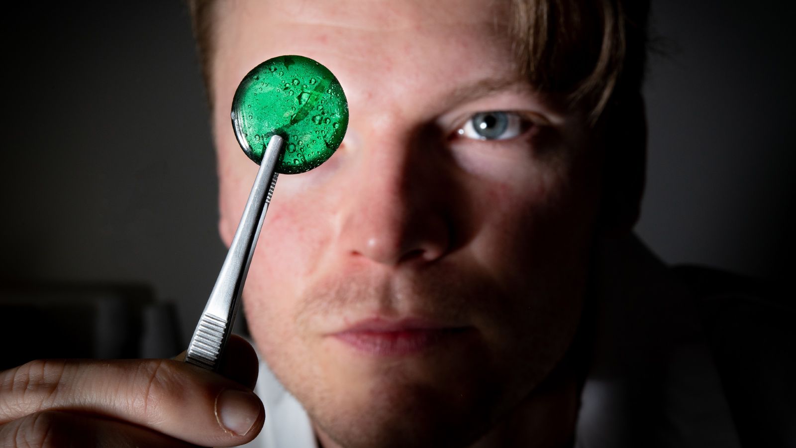 Dr Joe Schuyt in his laboratory holding a piece of fluorescent material