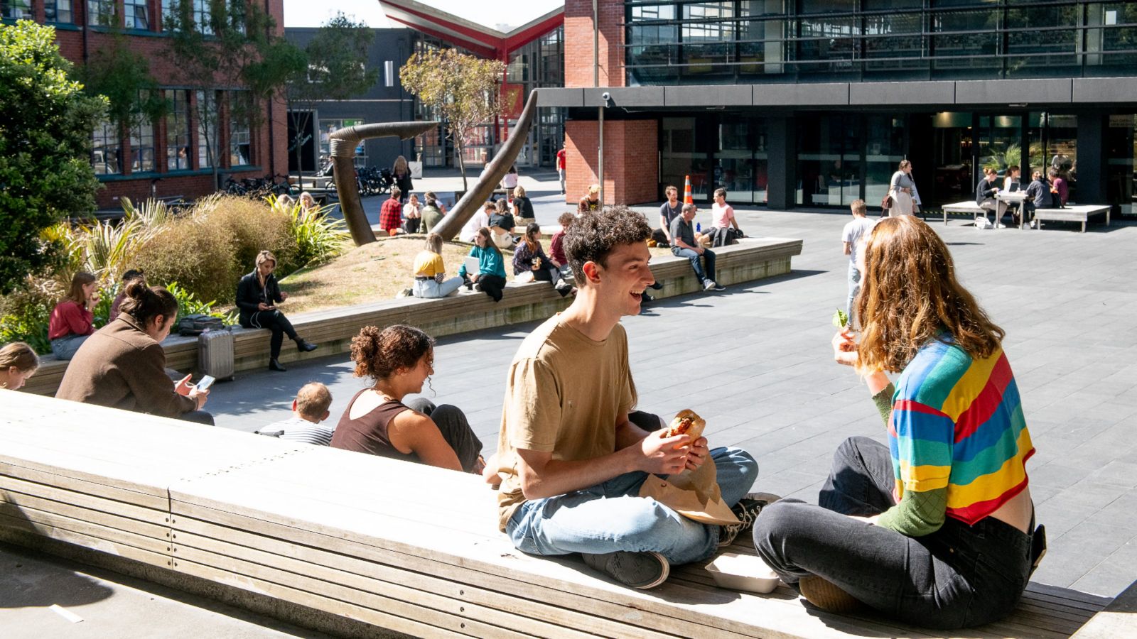 two students sit opposite each other eating lunch outside in the Tim Beaglehole courtyard