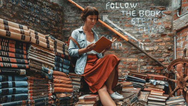Woman reading on piles of books