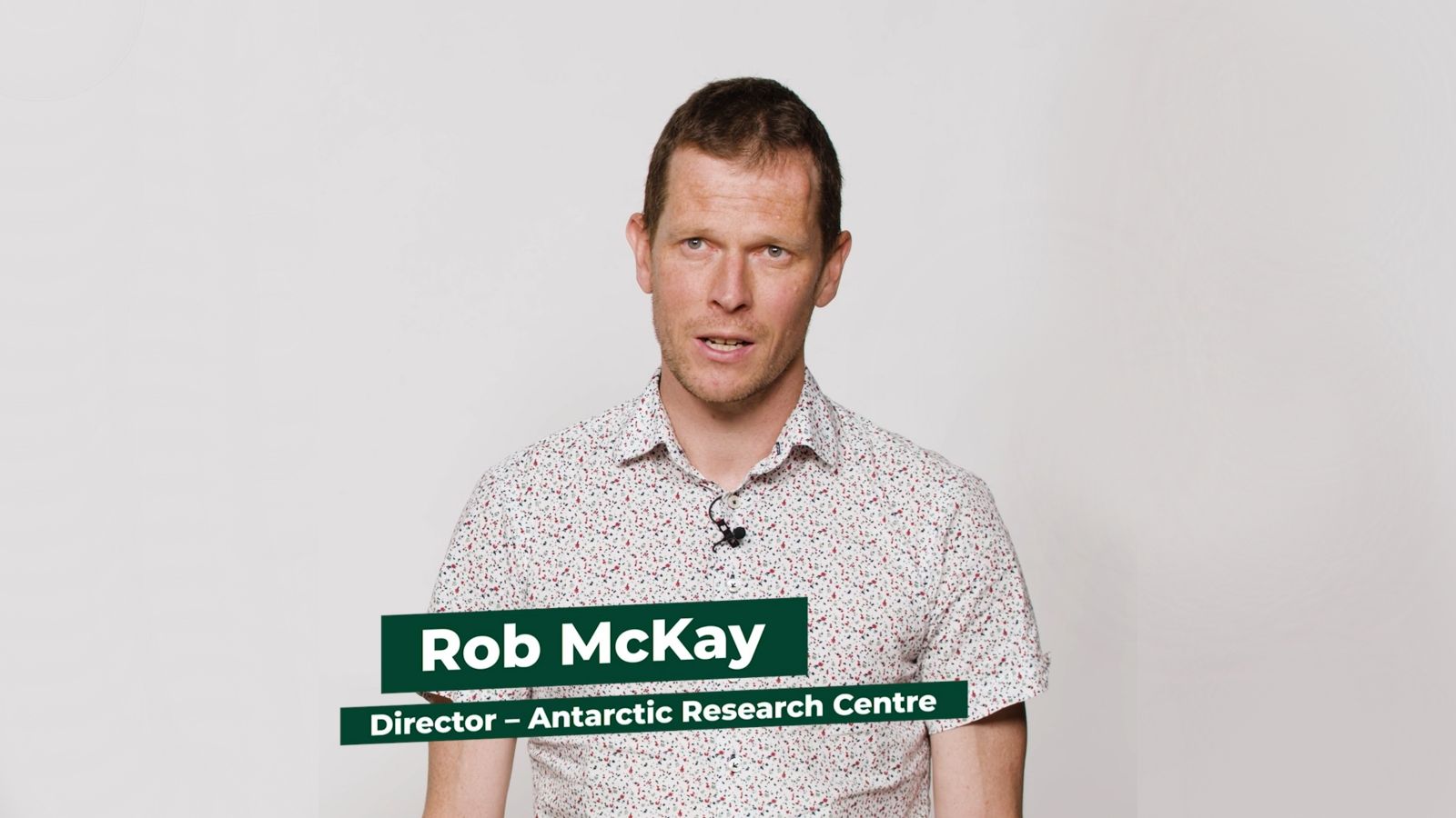 Associate Professor Rob McKay stands facing the camera against a white backrop