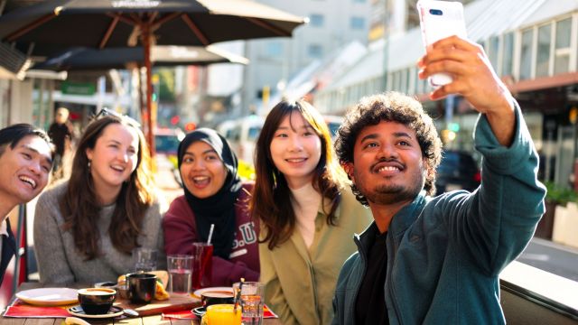 Students taking a selfie at a city cafe