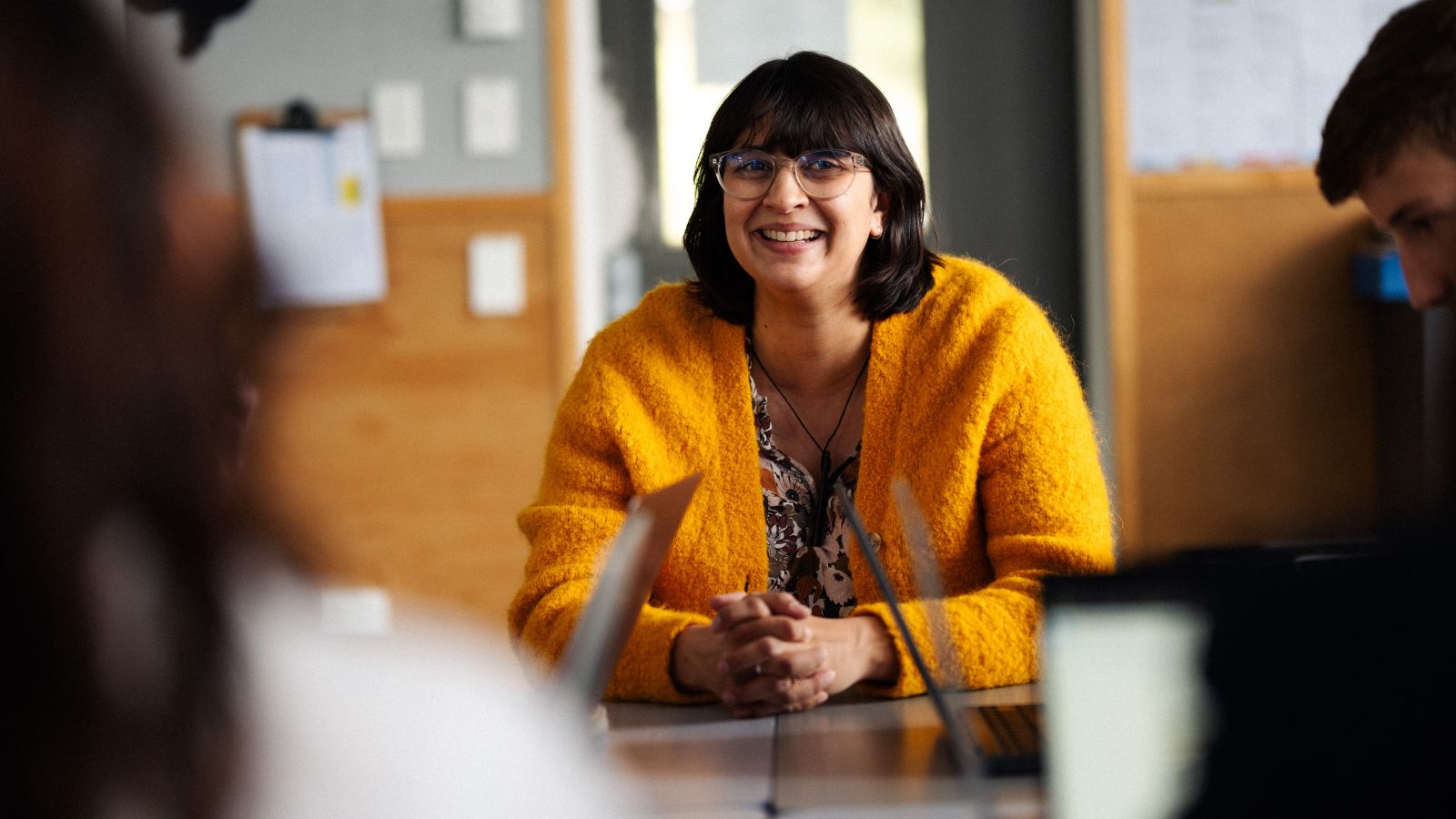 Teacher in yellow cardigan sitting with a group of students