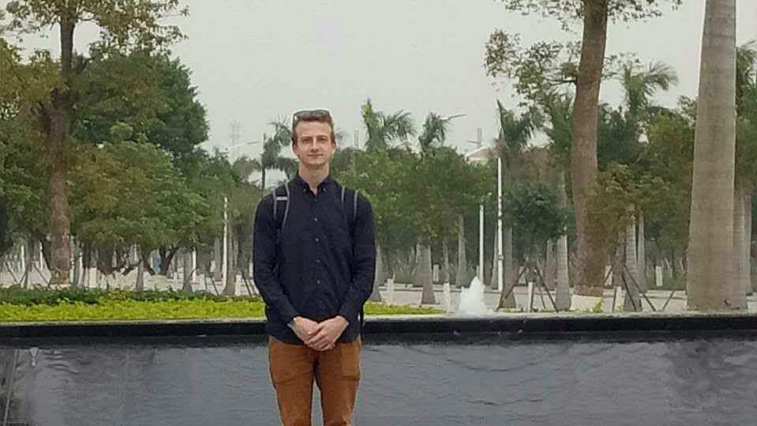 Alex on exchange in China, standing in front of a stream and trees.