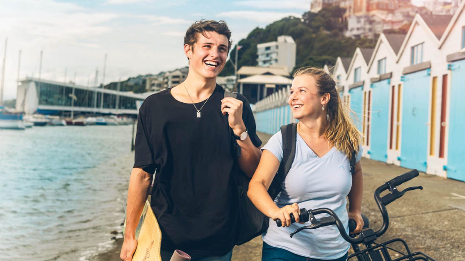 A male and female student are chatting and walking by the boatsheds at Oriental Bay, Wellington.