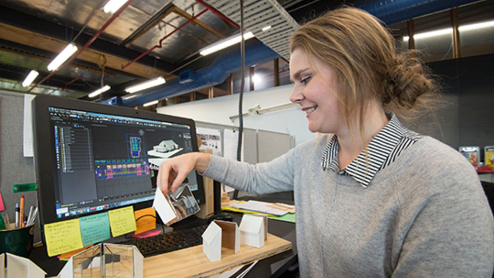 Alanah McCormick holding architecture models in front of her computer screen.