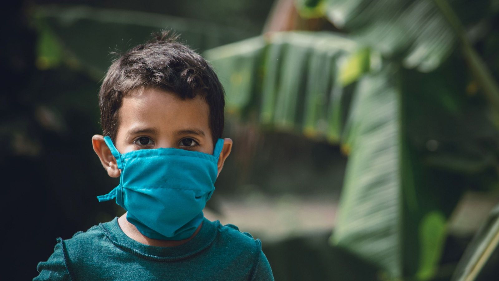 boy wearing mask against jungle trees
