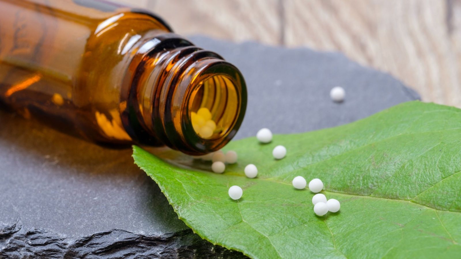 tiny white pills coming from a brown bottle on a leaf 