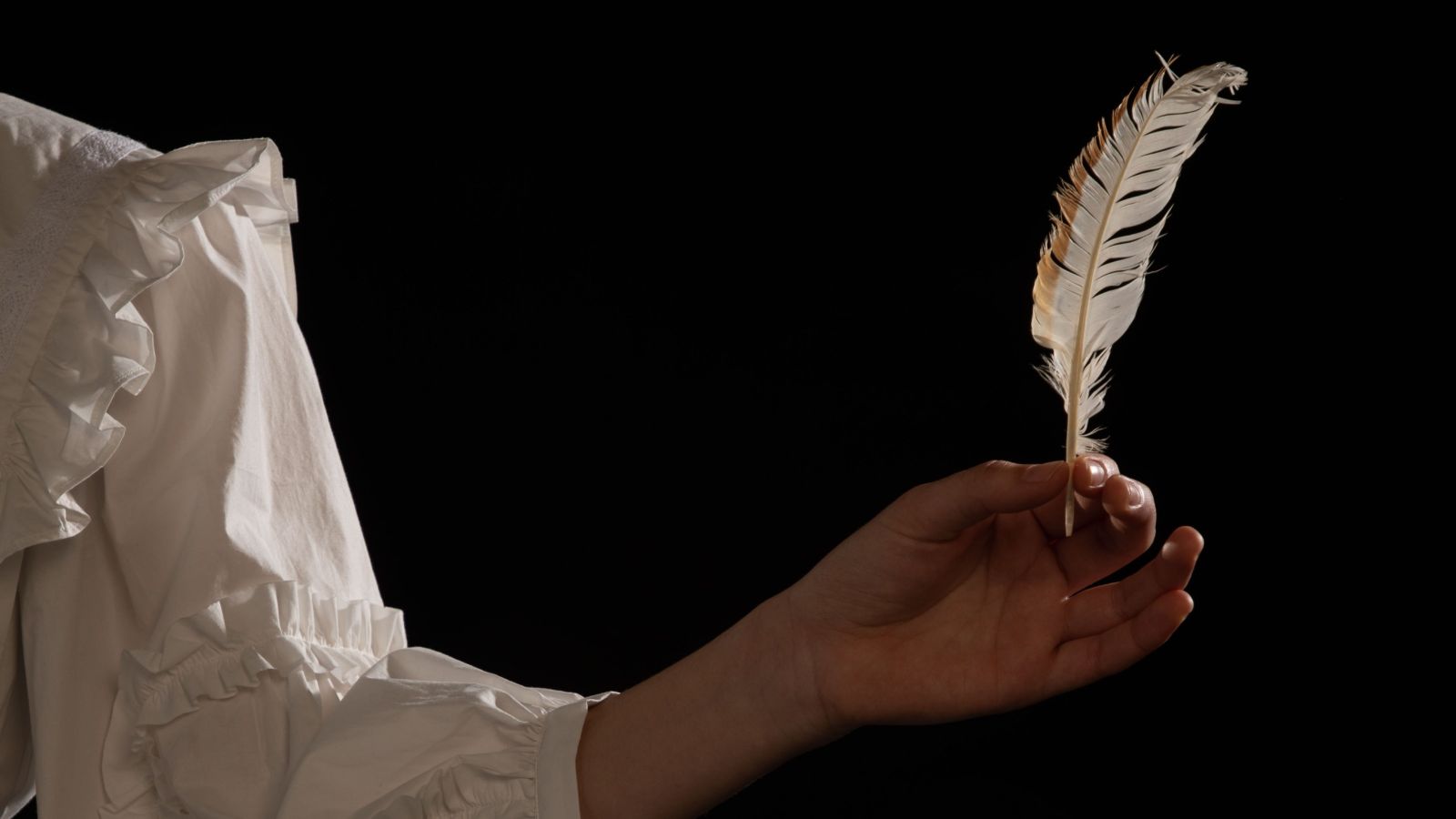 Hand doling a white feather