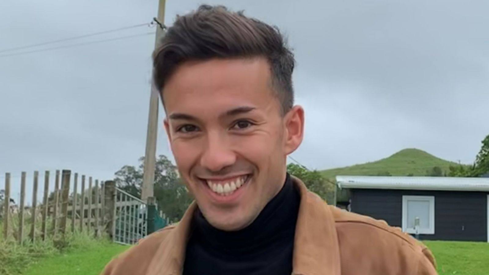 Young man smiling against rural backdrop