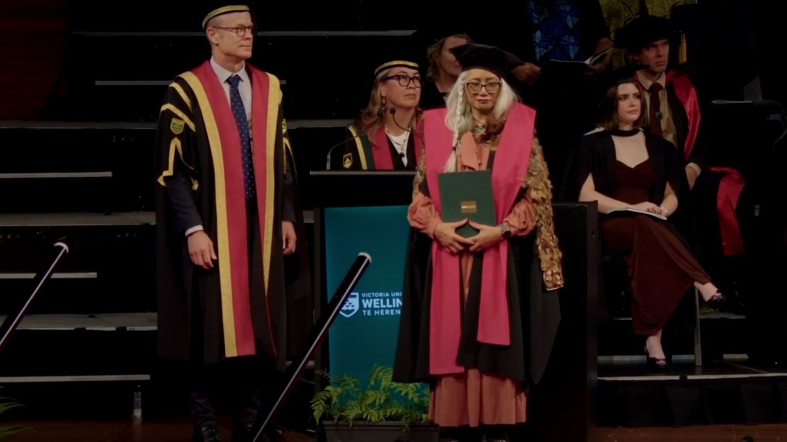 A group of colourfully dressed academics on the stage