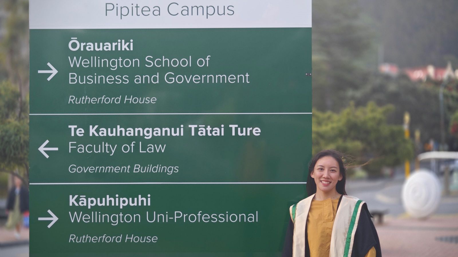 Echo stands in front of the wayfinding sign at Rutherford House, Pipitea Campus, Wellington