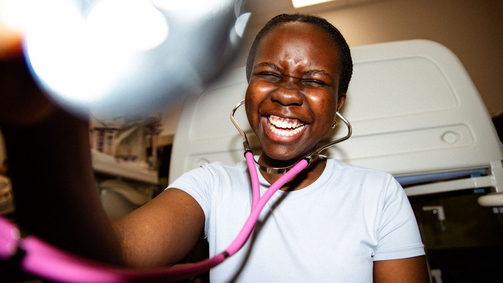 Student in a clinical setting wearing a stethoscope and smiling