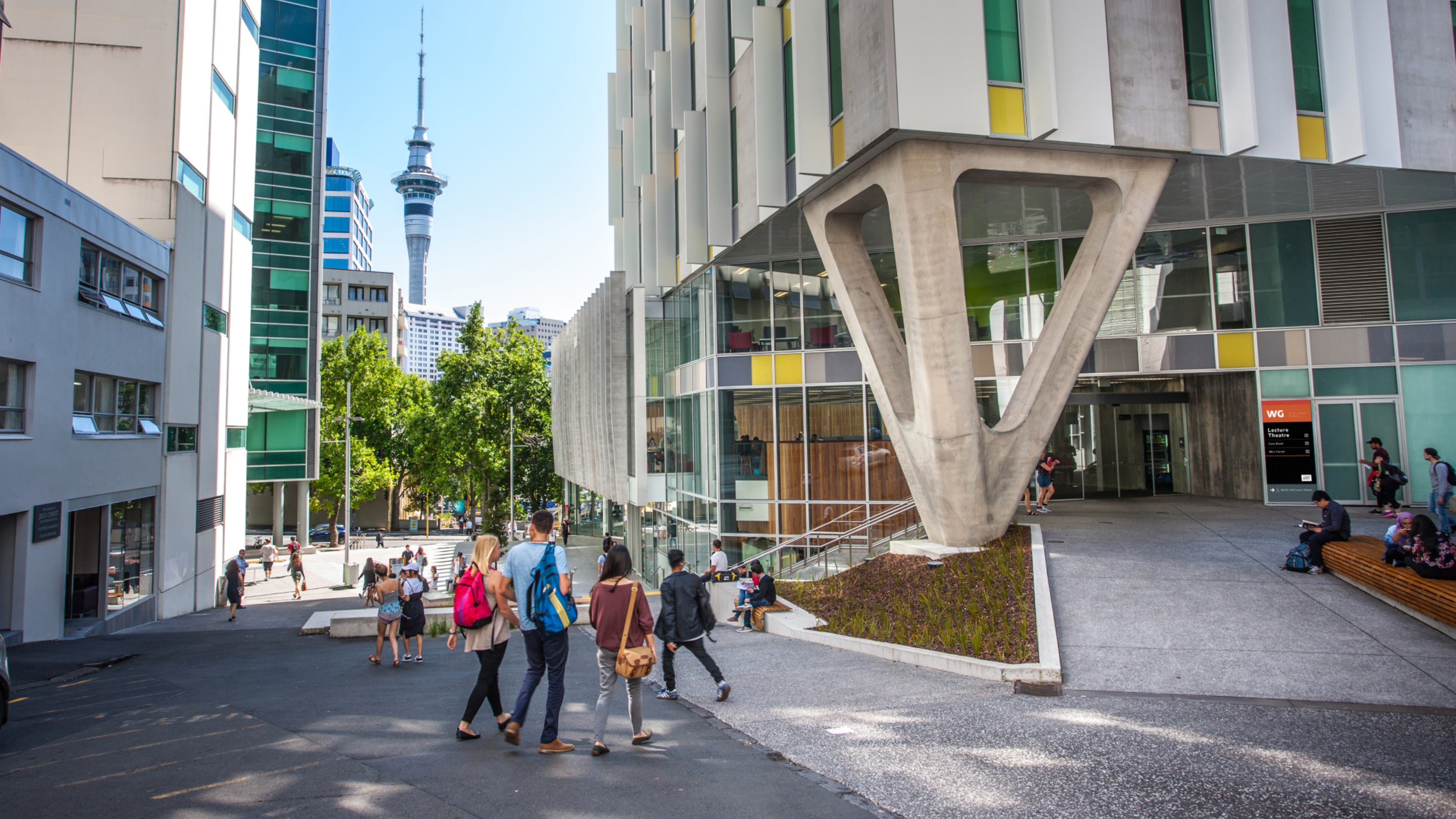 Landscape shot of AUT students walking into campus building, with the sky needle in the background