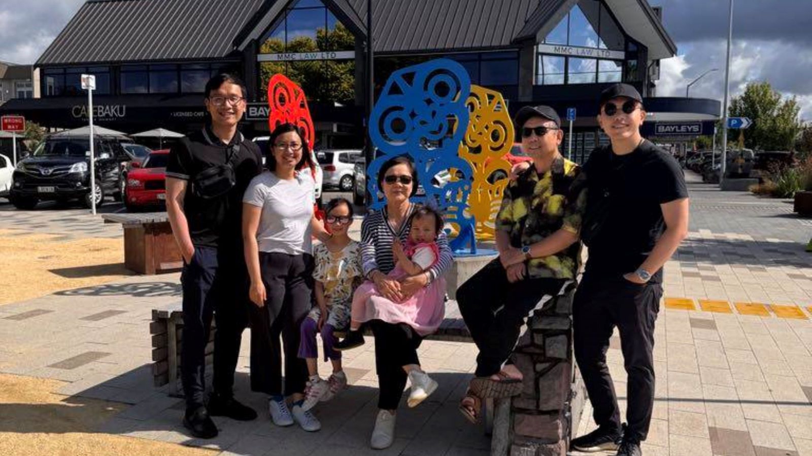 Cong with his family posing on bench for photo. 