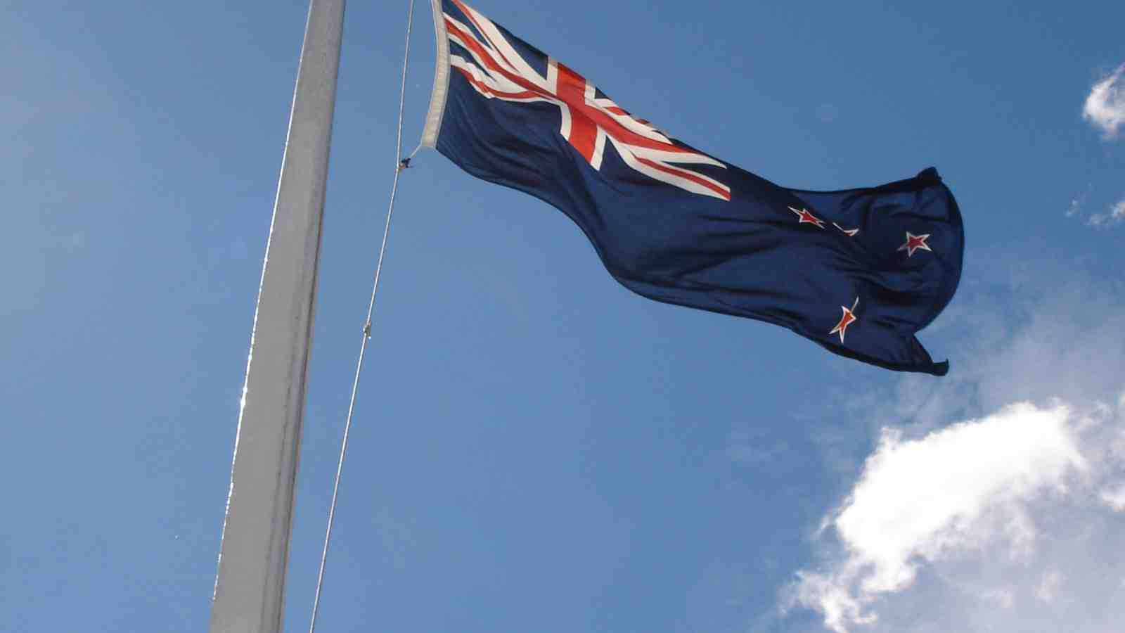 New Zealand flag with blue cloudy sky