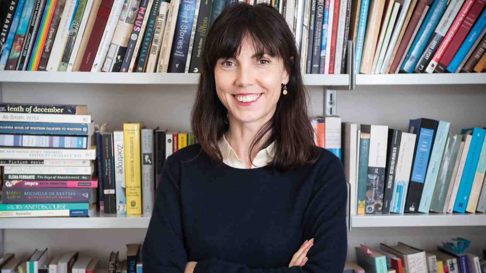 Senior lecturer Emily Perkins standing in front of a wall of books.