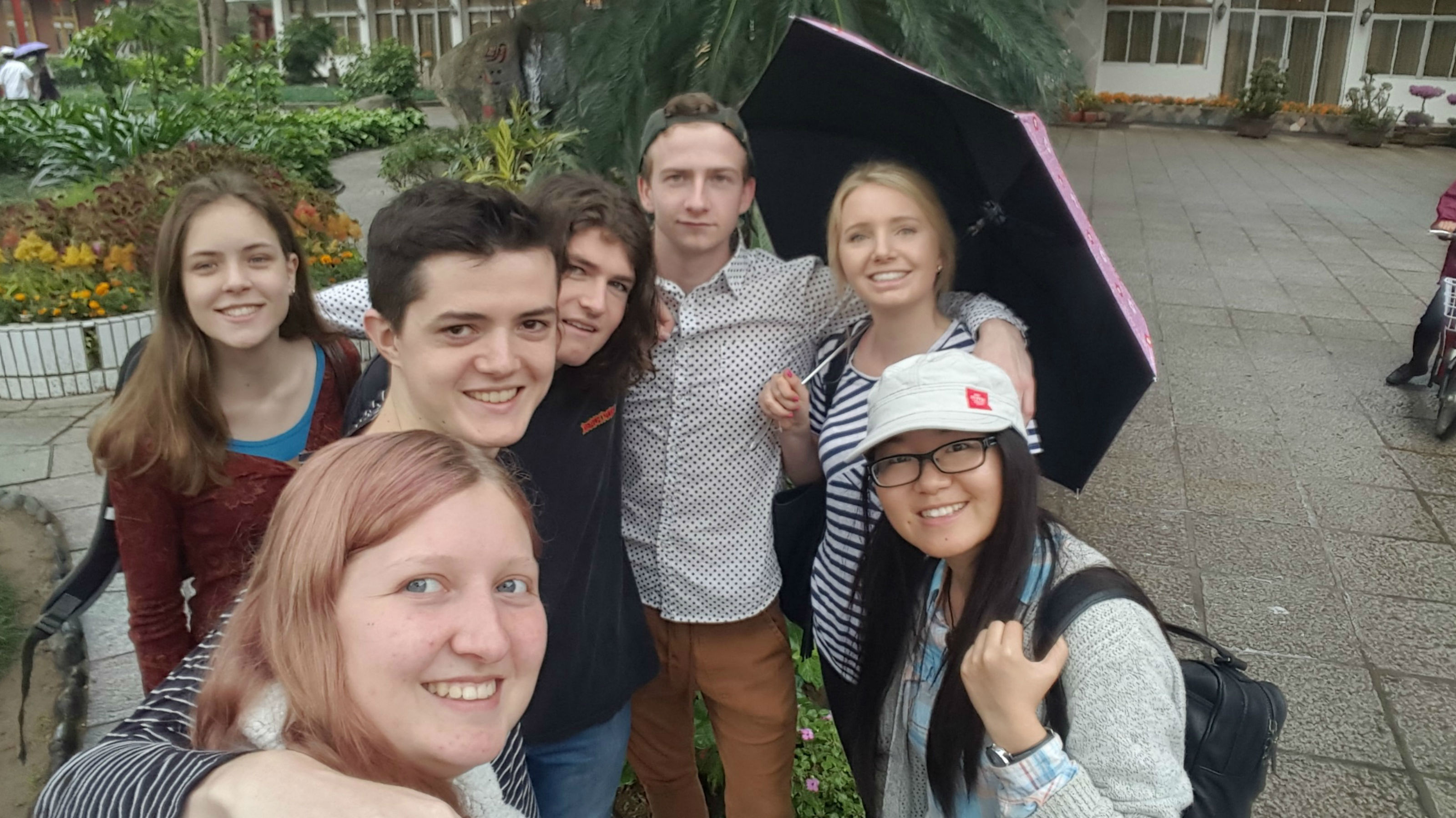 A group of Victoria students standing in a courtyard garden in Xiamen, China.