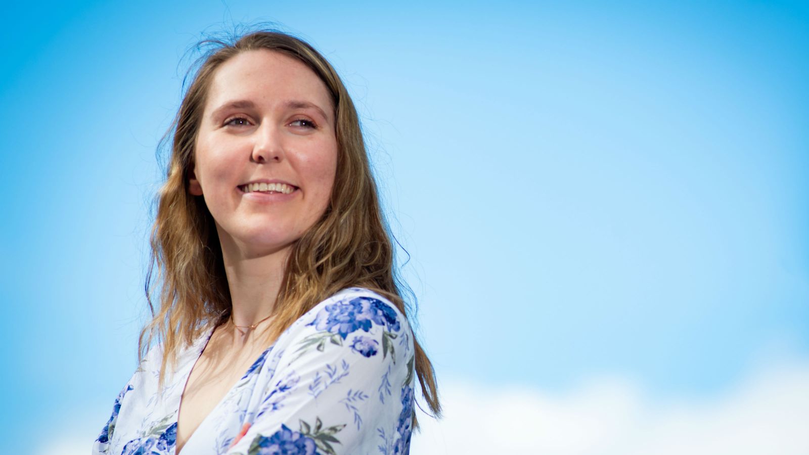 Forensic psychology researcher Annabelle Wride folds her arms and poses beneath an atmospheric blue sky.