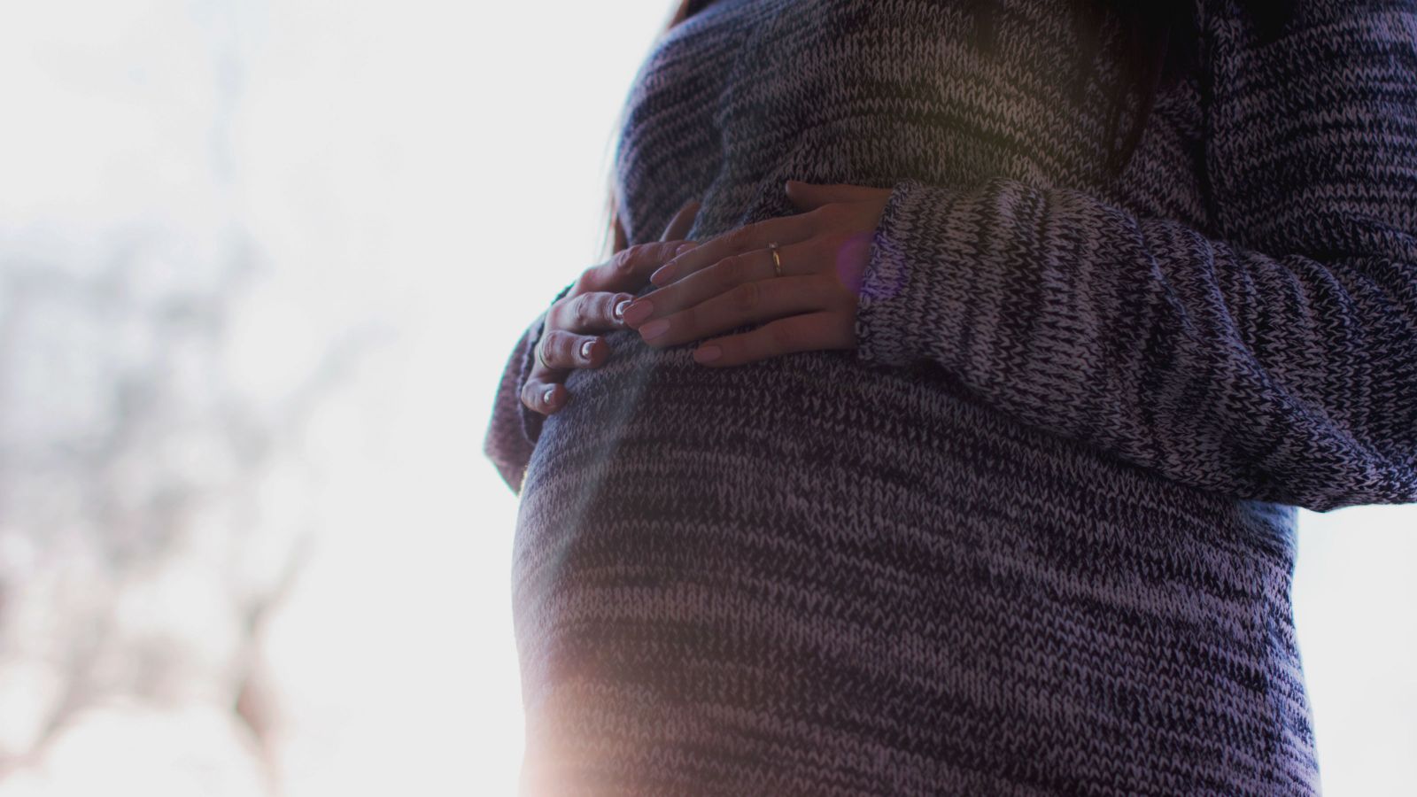 A pregnant woman holding her bump.