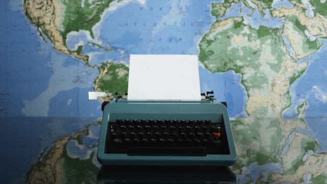 A typewriter sits in front a a world map.