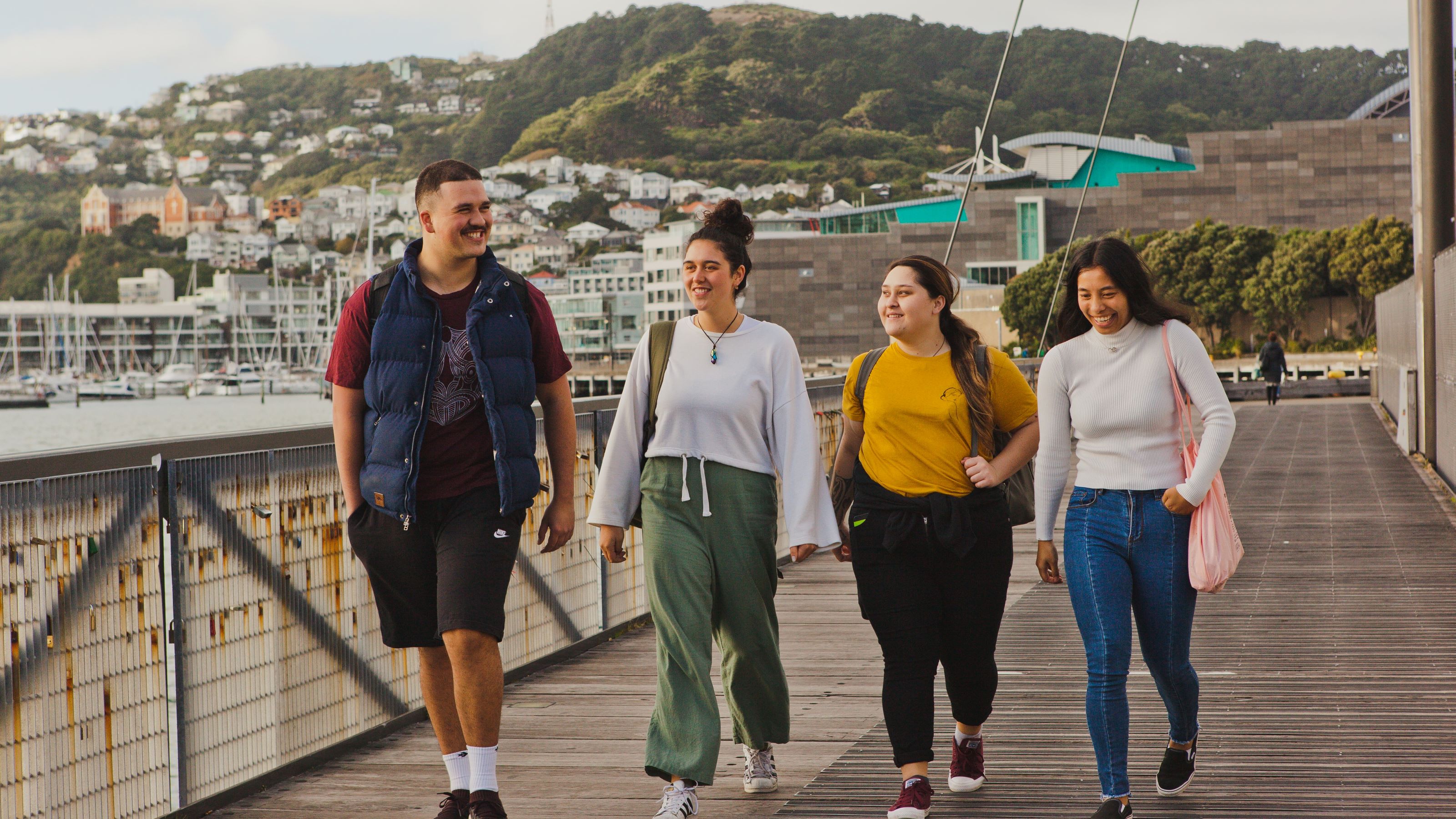 A group of 4 students walk along the Wellington waterfront