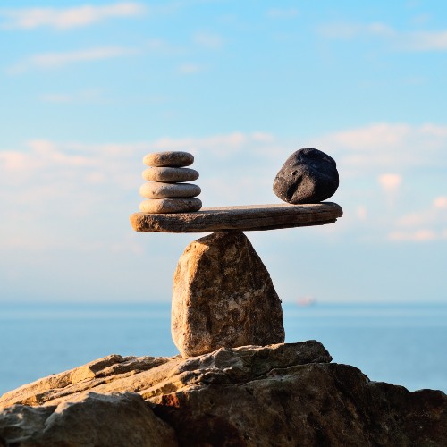 Equity Pile of rocks balancing one on top of the other, with a view of the horizon in the background..