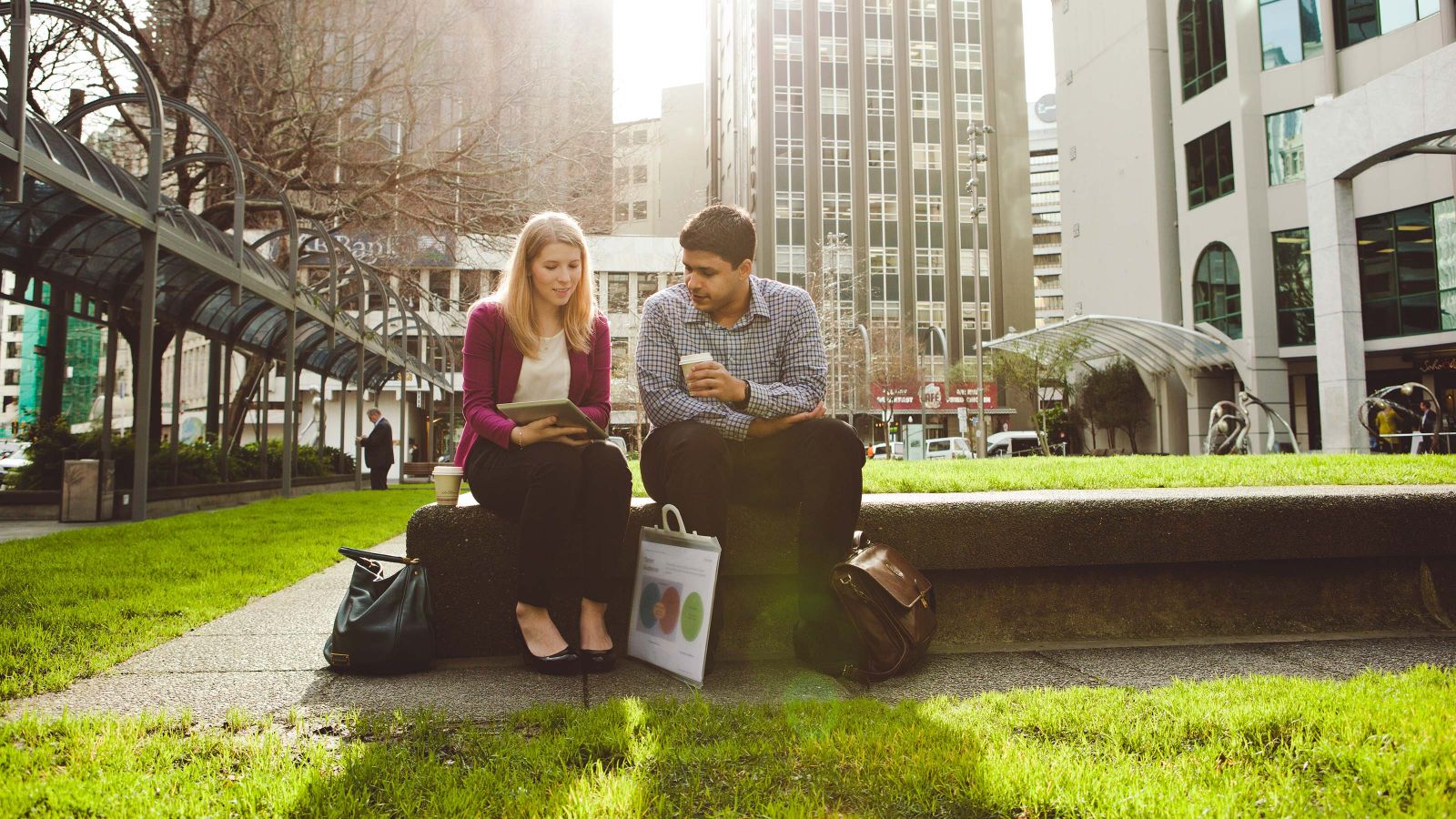 Two students sit beside eachother outside on a bench.