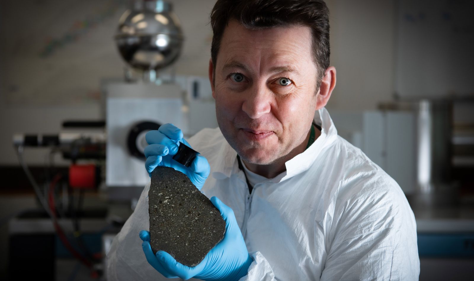Dr Bruce Charlier holding a slice of the Allende meteorite