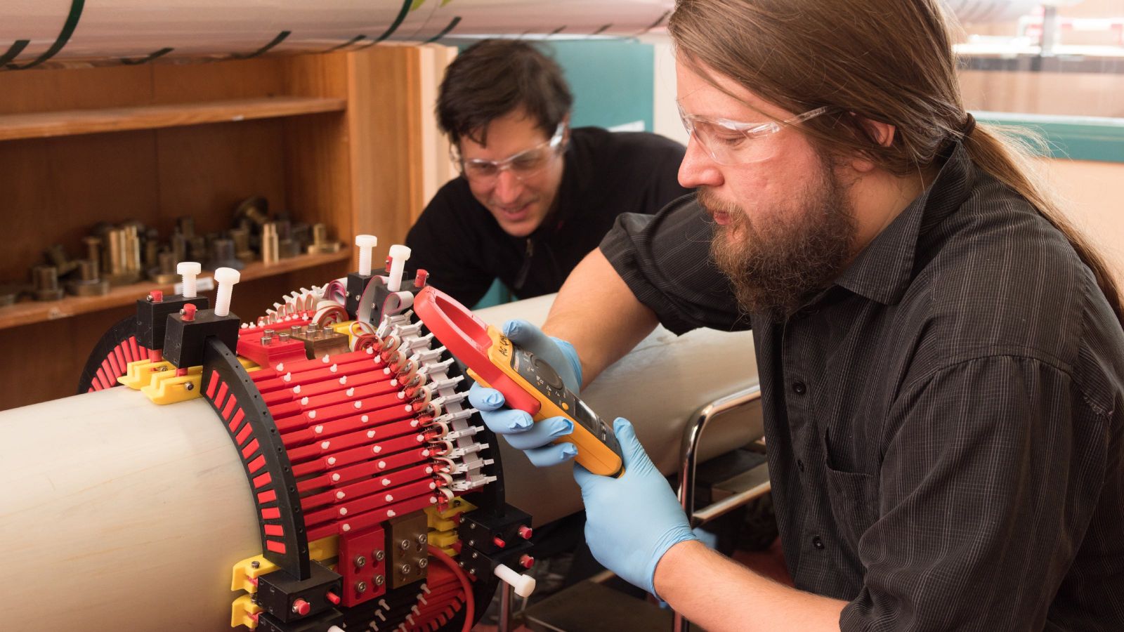 Two engineers using a device to detect defects within a pipe.