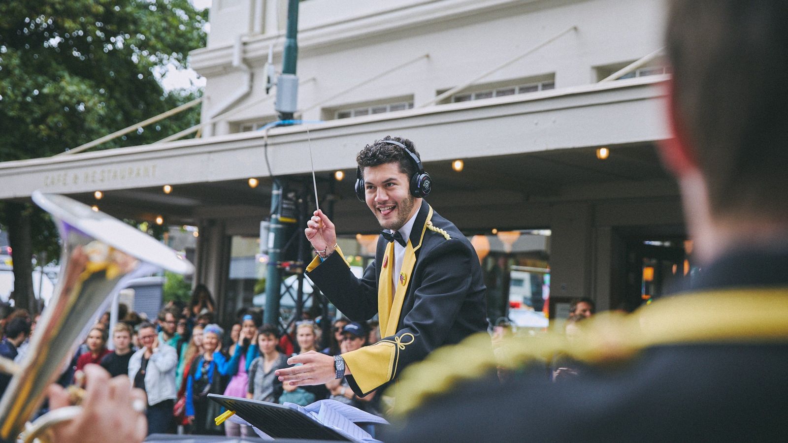 Conductor of a brass band wearing yellow and black.