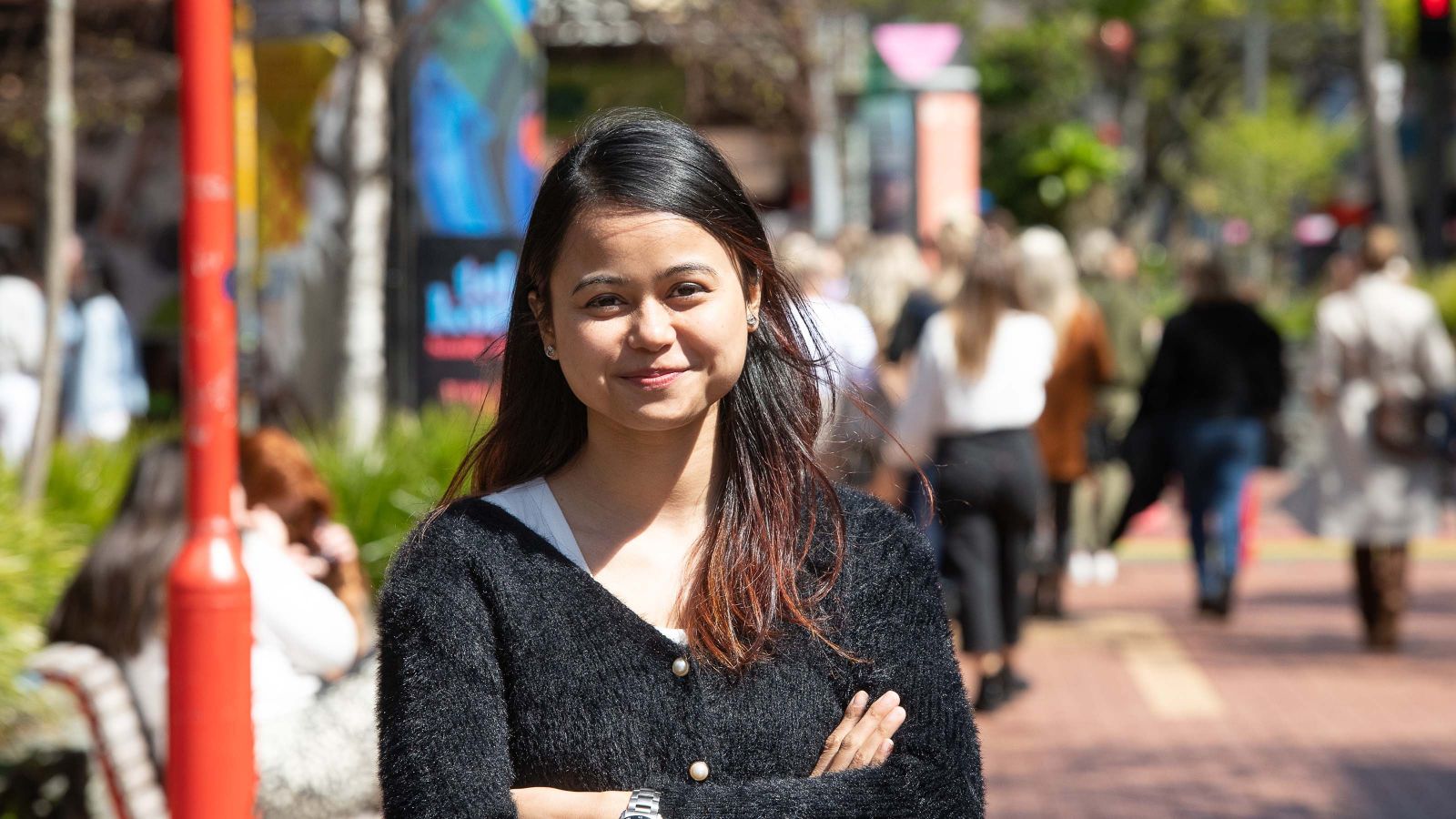 Swarnali stands on Cuba street with her arms crossed.