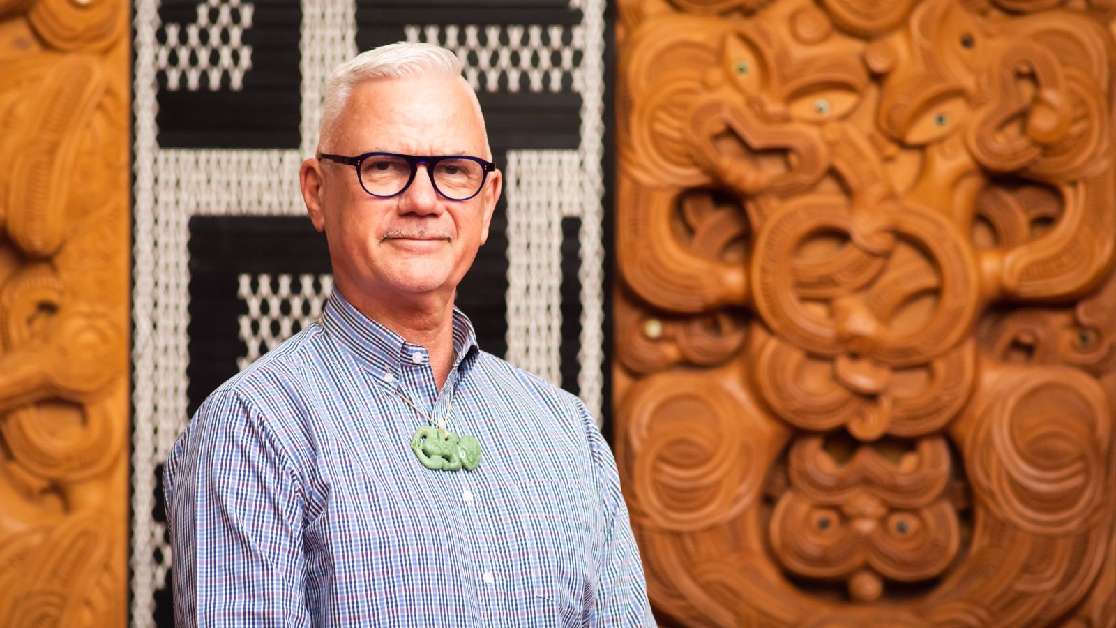 Man standing in front of Māori carving