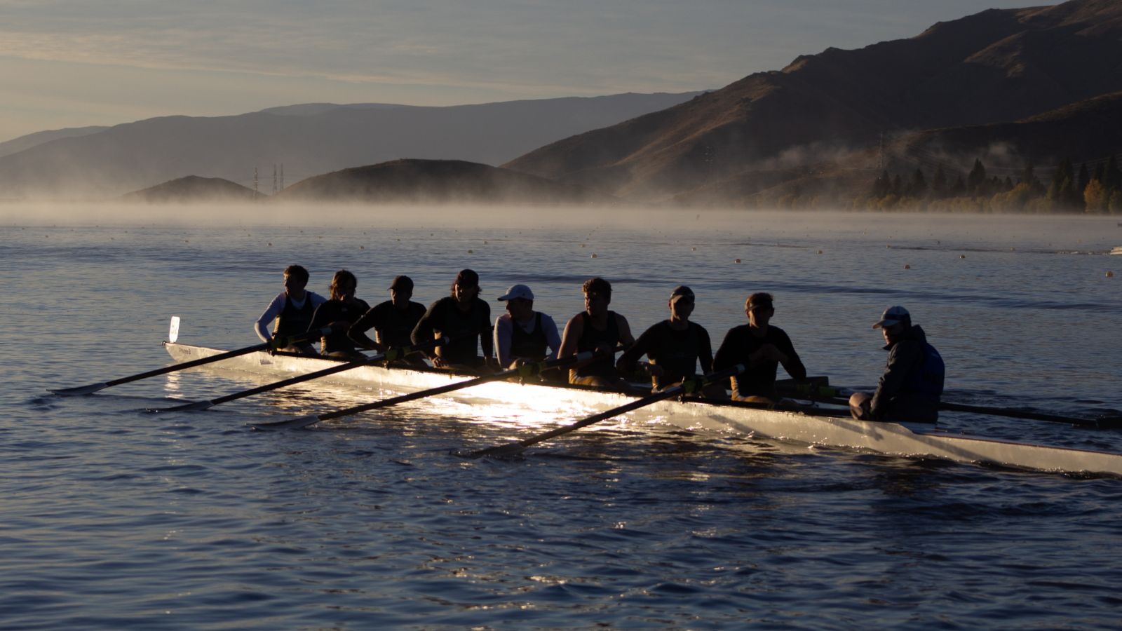 Rowing by sunrise in Wellington harbour, with fog over the sea.