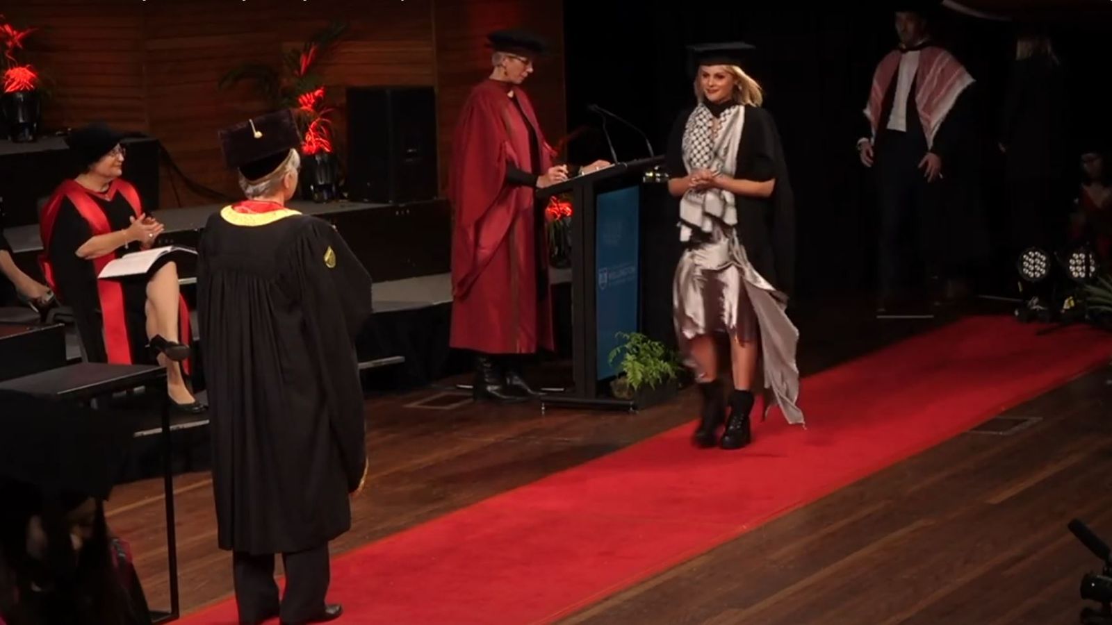 A graduate walking across the stage to receive their degree.