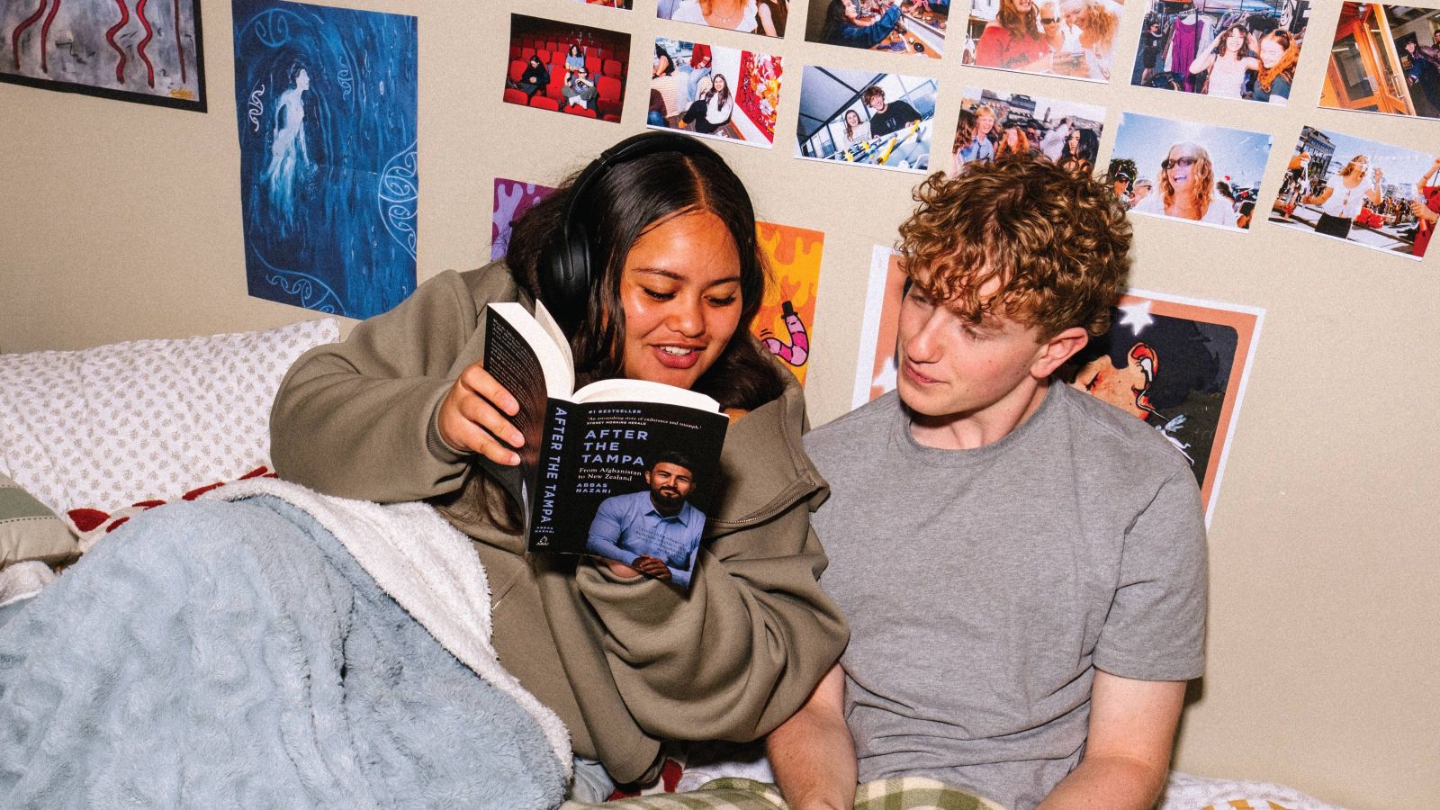two students in a halls of residence bedroom hanging out reading a book
