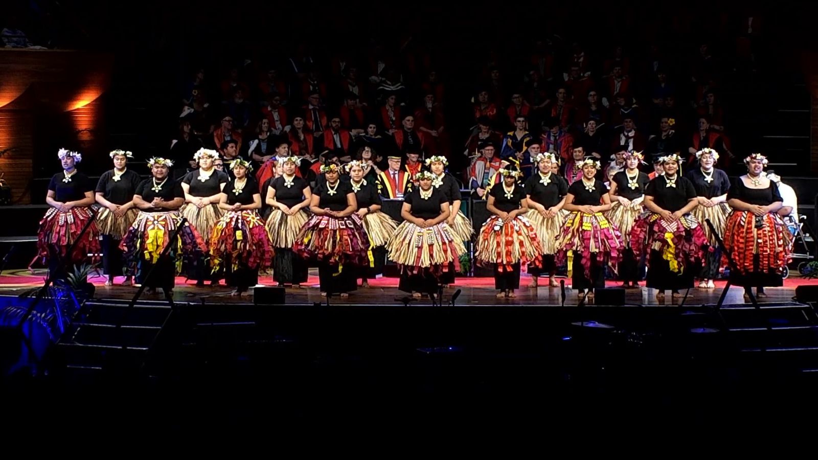 Group performing a cultural dance on stage during a graduation ceremony.