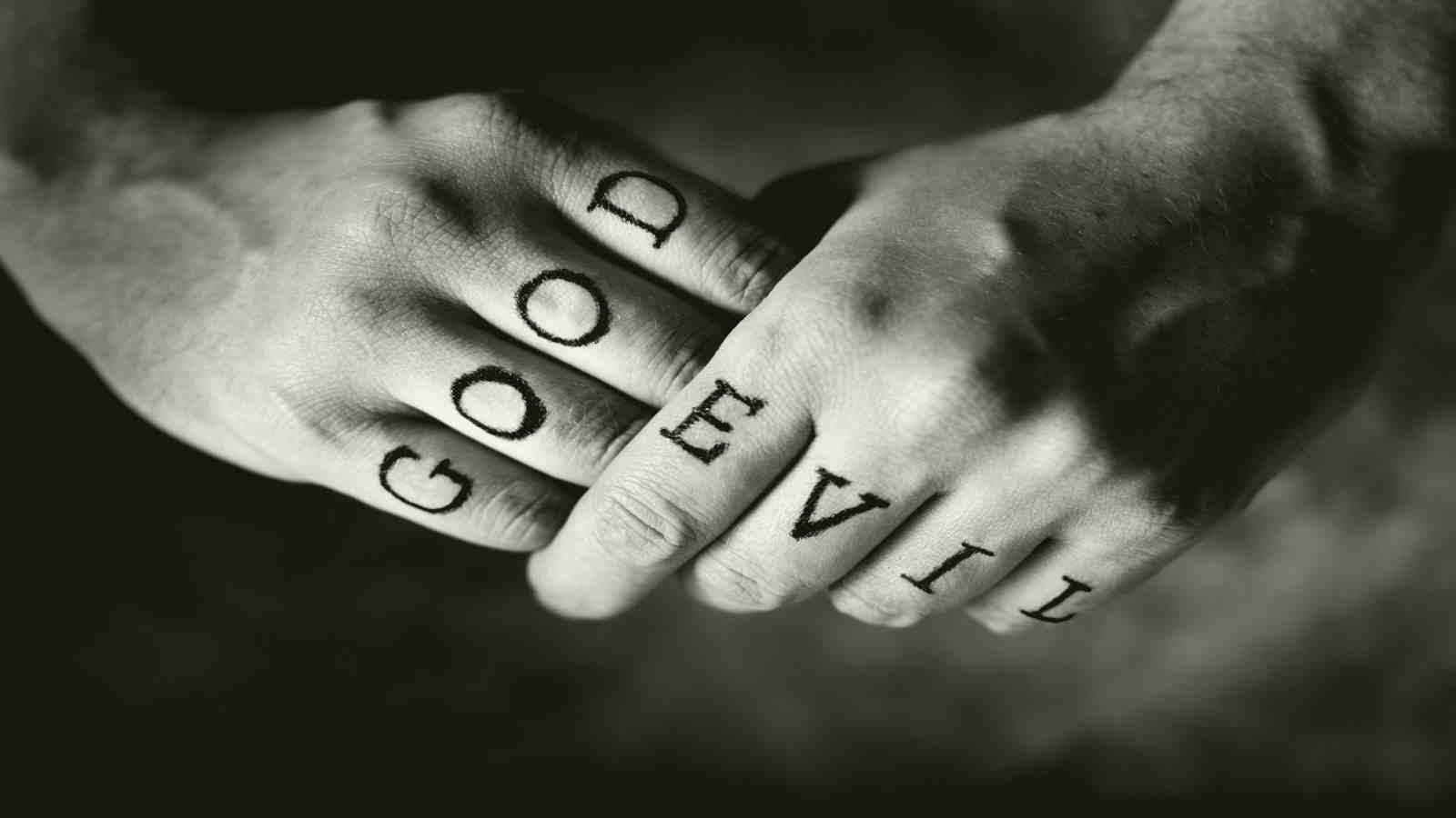 good and evil written across the knuckles of hands