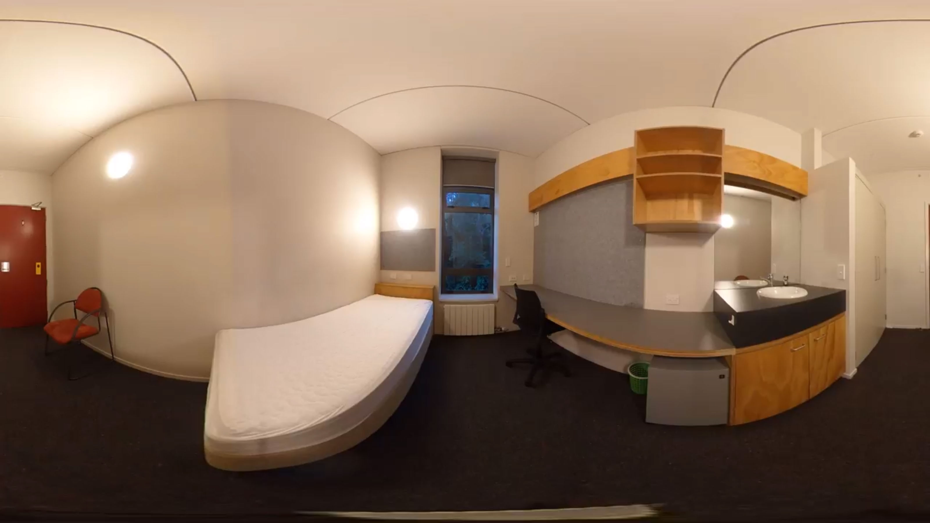 A panoramic view of a bedroom in the Te Whānau wing with a single bed, a desk, and a sink.