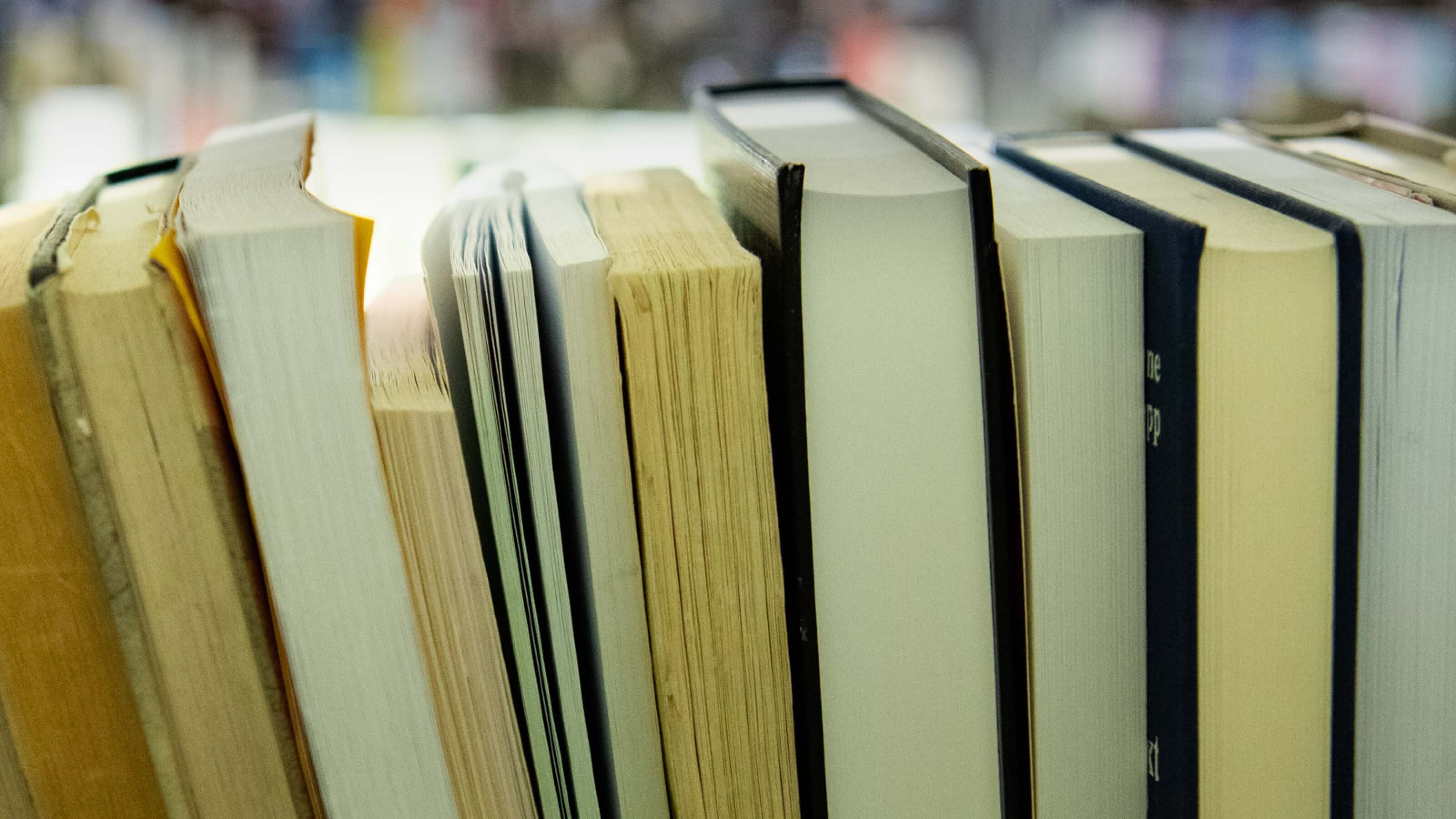 An image of books on a shelf as viewed from the perspective of looking at the pages between the covers.
