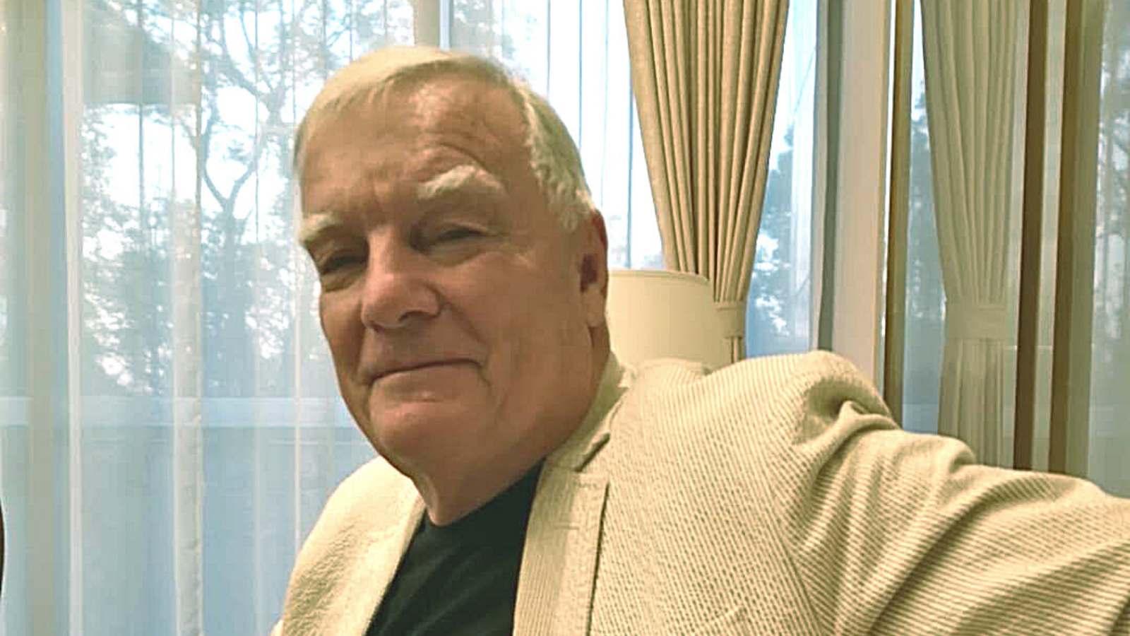 Man with white jacket and white hair on couch