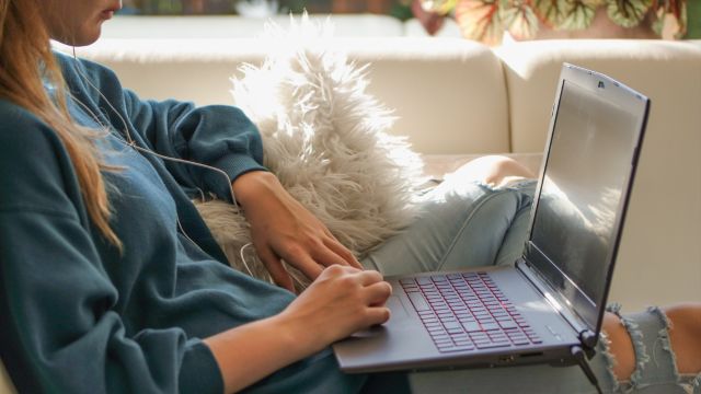 A person sitting o a sofa with a laptop on their lap.