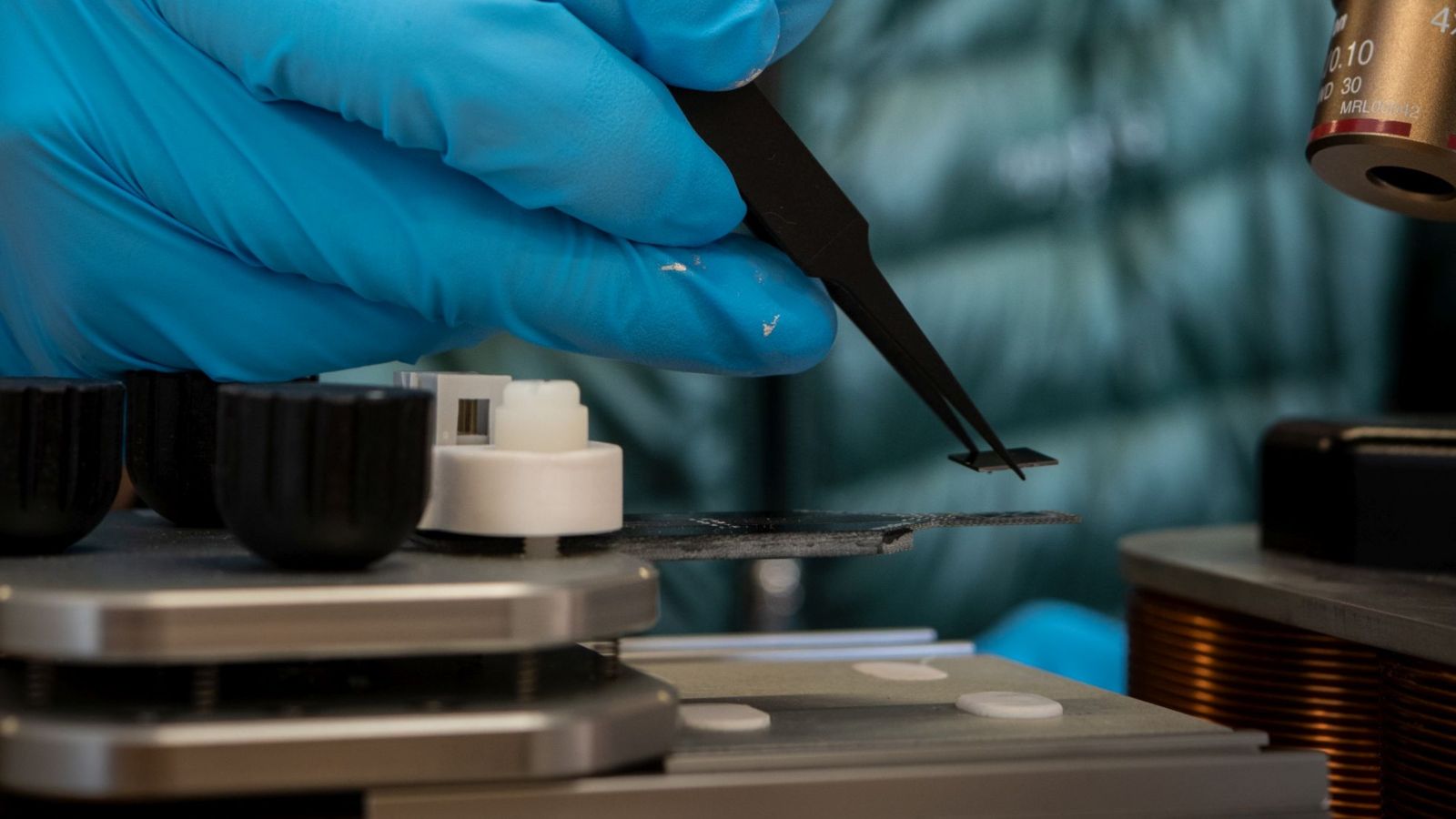 Gloved hands placing a micro-chip sensor onto a slide a near a microscope