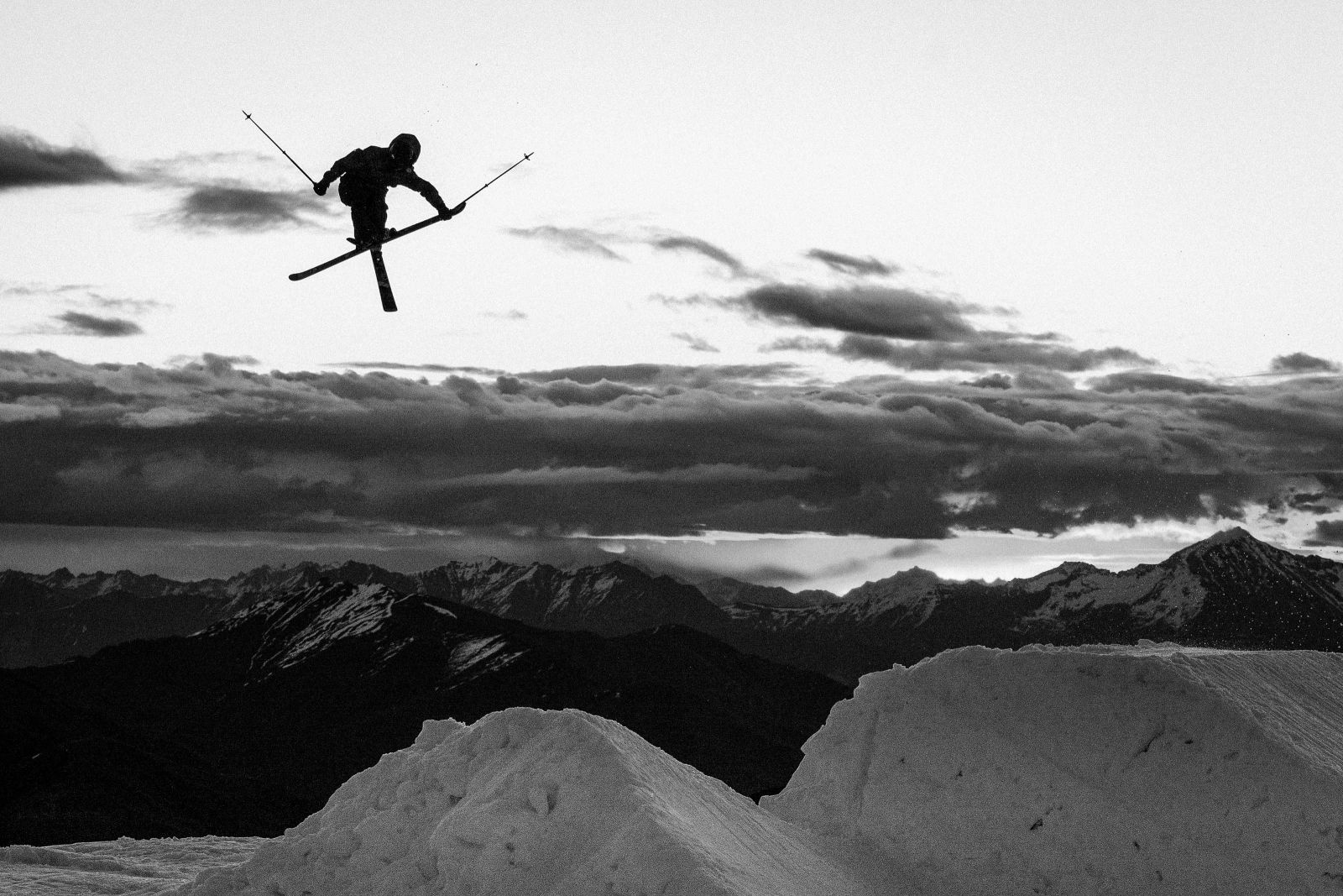 Black and white image of a skier jumping. 