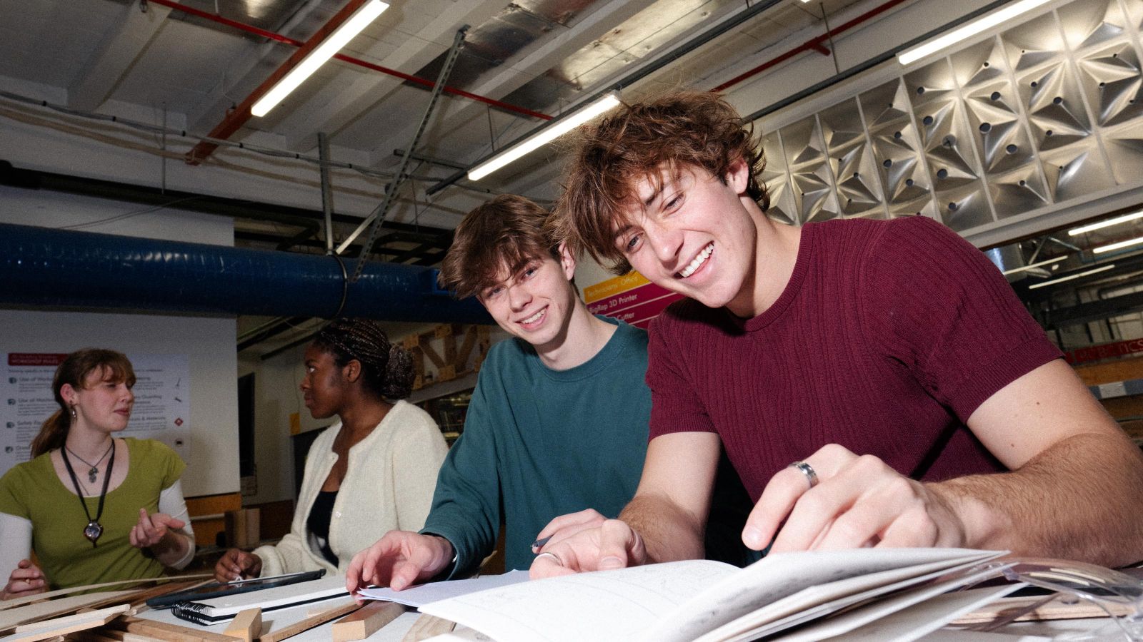 4 students in a classroom setting, sitting with open books in front of them