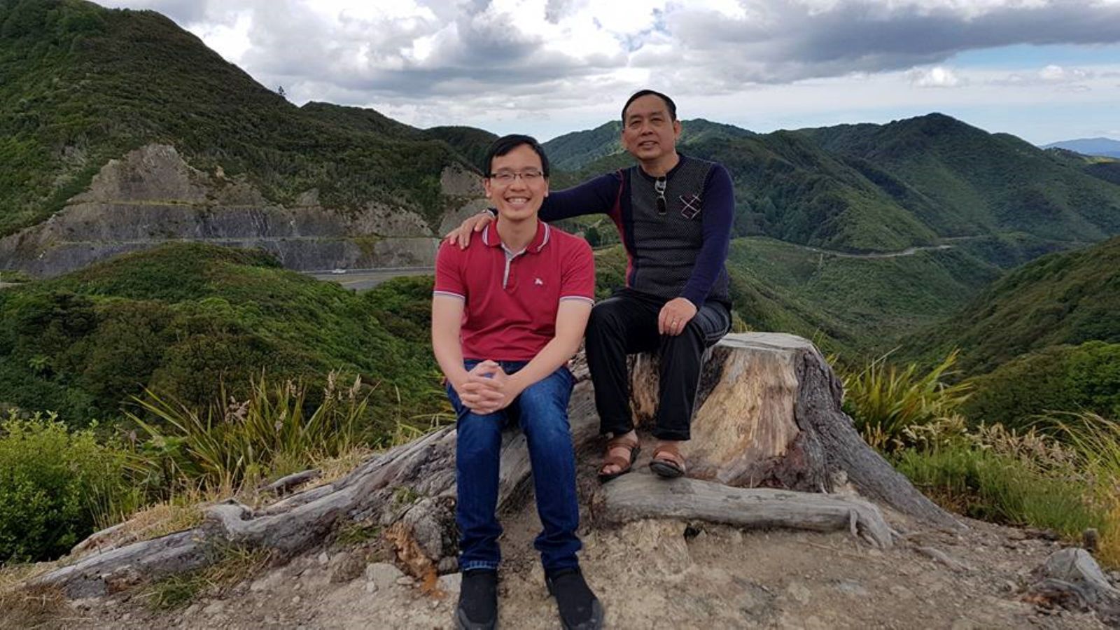 Cong with his father in the mountains sitting side-by-side. 