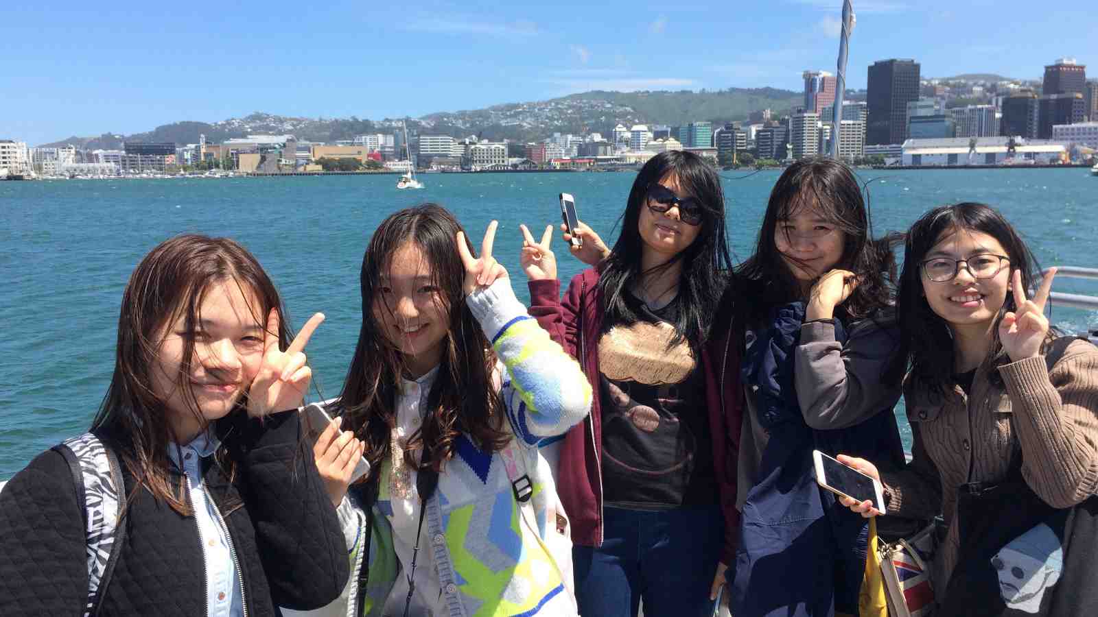 Chinese students smile on a boat in Wellington harbour.