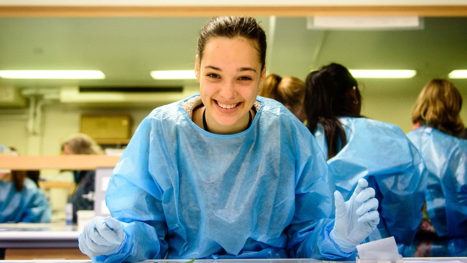 A young woman smiling in laboratory personal protective gear. 